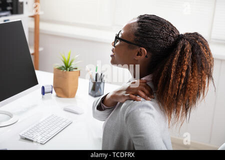 Businesswoman souffrant de douleur à l'épaule tout en travaillant à l'Office de Tourisme Banque D'Images