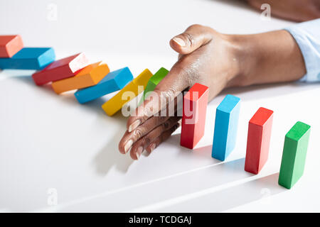 Close-up of a Businesswoman part l'arrêt de dominos colorés de tomber sur Office 24 Banque D'Images