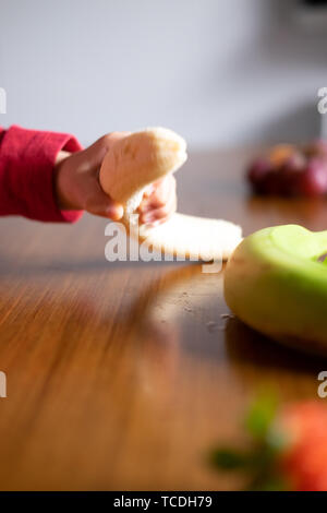 La main de bébé manipuler différents fruits sur une table en bois Banque D'Images