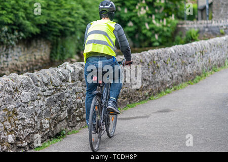 Un cycliste masculine monte un vélo en toute sécurité - Casque, Veste haute visibilité, feux de vélo Banque D'Images