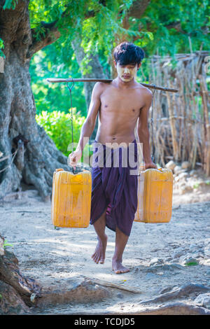 Fermier birman transportant des seaux remplis d'eau dans un village près de Bagan Banque D'Images