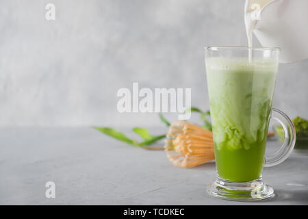 Thé matcha vert et verser dans le verre de lait latte sur table gris. Vue d'en haut. L'espace pour le texte. Close up. Banque D'Images