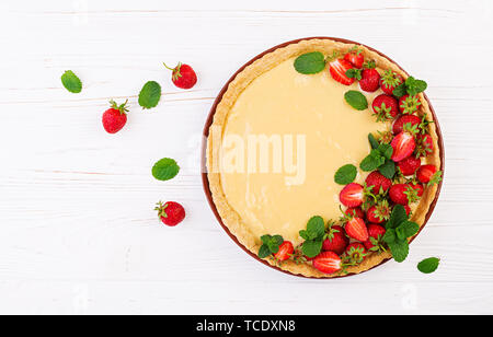 Tarte aux fraises et crème fouettée décoré de feuilles de menthe sur fond clair. Vue d'en haut Banque D'Images