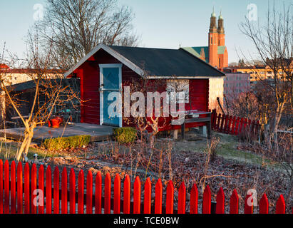 Allotissement rouge Falun cottage et clôture avec les tours de Hogalid en arrière-plan, l'allotissement Tantolunden, jardins, Sodermalm Stockholm, Suède Banque D'Images