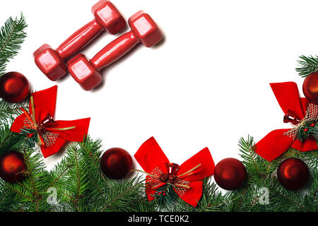 Noël et Nouvel An sport avec haltères, fond rouge vert sapin branches boules de verre rouge et red bows cloches sur fond blanc. Banque D'Images