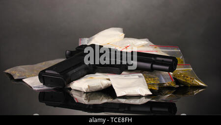 La cocaïne et la marihuana en paquets avec pistolet sur fond gris Banque D'Images