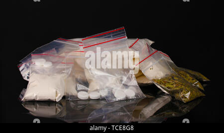 La cocaïne et la marihuana en paquets sur fond noir Banque D'Images