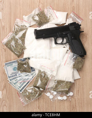 La cocaïne et la marihuana en paquets, des dollars avec pistolet sur fond de bois Banque D'Images