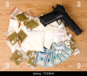 La cocaïne et la marihuana en paquets, des dollars avec pistolet sur fond de bois Banque D'Images