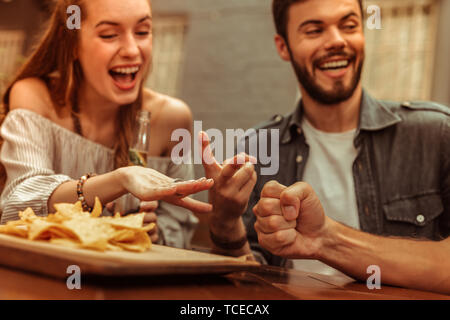 Une soirée entre amis. Photo en gros plan d'appel lumineux rayonnant sourire les jeunes-adultes amis partageant un rire et jouer à des jeux tout en étant assis à t Banque D'Images