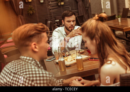 Homme seul. Dark-haired insatisfait bon-à-jeunes barbus attrayant hot guy wearing blue shirt à flirter avec envie à son partenaire tout en Banque D'Images