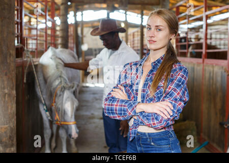 Portrait de jeune fille travailleuse agricole debout à horse stable Banque D'Images