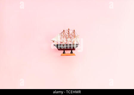 Petit jouet bateau en bois sur fond rose. Modèle de navire à voile Banque D'Images