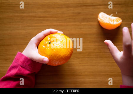 La main de bébé manipuler différents fruits sur une table en bois Banque D'Images