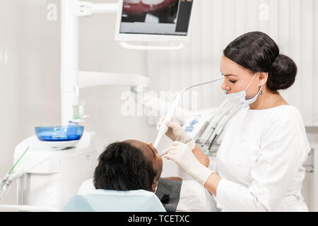 Avec une inspection caméra macro dentaire et affiche le résultat sur le moniteur. Jeune femme dentiste traitant des traitements de canaux dans la clinique dentaire. Man Banque D'Images