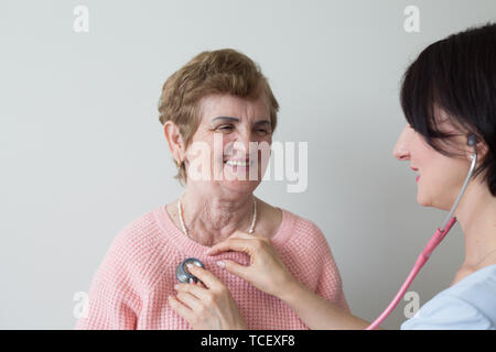 Infirmière avec smiling elderly female patient with stethoscope medical exam Banque D'Images
