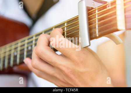 Musician playing style doigt sur guitare acoustique avec capo Banque D'Images