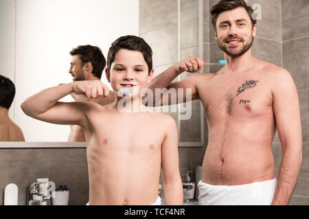 Smiling fils et papa se brosser les dents dans la salle de bains Banque D'Images