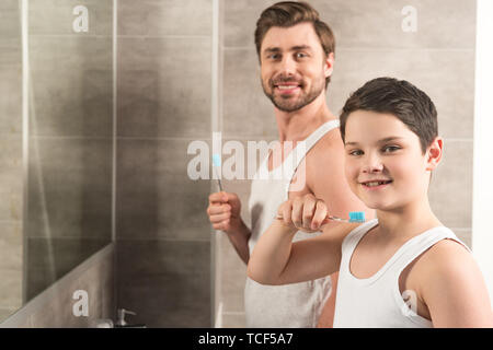 Smiling fils et papa se brosser les dents le matin dans la salle de bains Banque D'Images