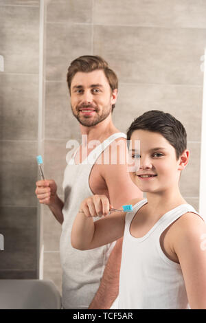 Smiling fils et papa se brosser les dents le matin dans la salle de bains Banque D'Images