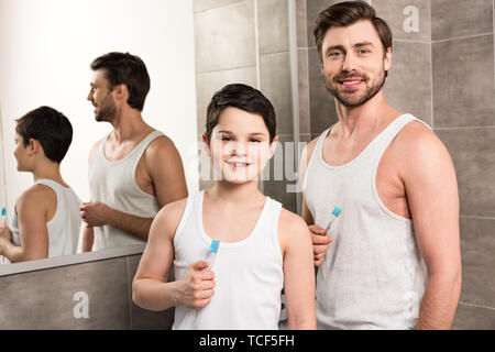 Smiling fils et papa se brosser les dents le matin dans la salle de bains Banque D'Images