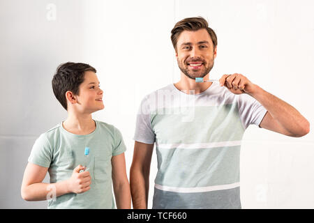 Smiling fils et père barbu se brosser les dents dans la salle de bains Banque D'Images