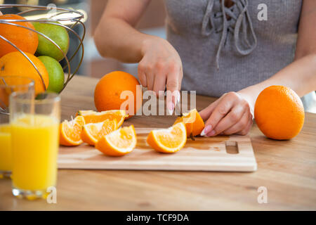 La cuisson des aliments, et le concept du véganisme, la vigueur et la saine alimentation - close up of female coupe manuelle sur des tranches d'orange. Banque D'Images