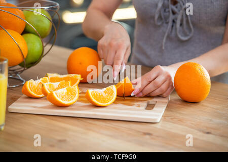 La cuisson des aliments, et le concept du véganisme, la vigueur et la saine alimentation - close up of female coupe manuelle sur des tranches d'orange. Banque D'Images