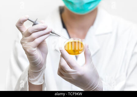 Close-up méconnaissable femme scientifique laissant tomber en liquide de couleur plaque de test . Banque D'Images