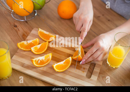 La cuisson des aliments, et le concept du véganisme, la vigueur et la saine alimentation - close up of female coupe manuelle sur des tranches d'orange. Banque D'Images