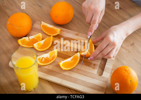 La cuisson des aliments, et le concept du véganisme, la vigueur et la saine alimentation - close up of female coupe manuelle sur des tranches d'orange. Banque D'Images