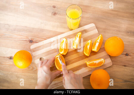 La cuisson des aliments, et le concept du véganisme, la vigueur et la saine alimentation - close up of female coupe manuelle sur des tranches d'orange. Banque D'Images