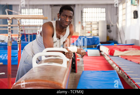 L'homme afro adultes sportswear en faisant des exercices sur appareils de gymnastique acrobatique dans hall Banque D'Images