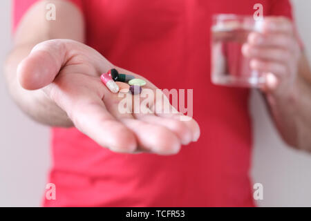 Un homme avec un verre d'eau dans sa main. L'élévation de la température corporelle. Comprimés contre le rhume et la grippe. La prévention et le renforcement de l'immunité. Le concept de la santé Banque D'Images