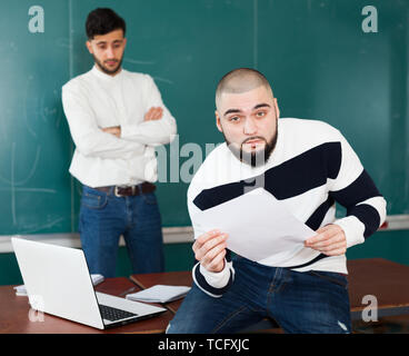 Portrait de deux jeunes gars travaillant sur leur projet étudiant près de blackboard in classroom Banque D'Images