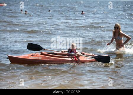 Une adolescente qui pousse son jeune frère dans un kayak le long du front de mer Banque D'Images