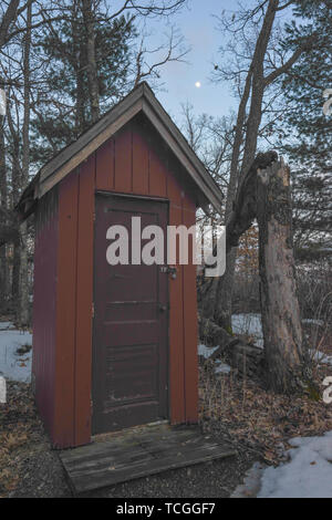 Outhouse abandonnés rouge dans les bois sous la lune et la lune au crépuscule avec un arbre tombé - prise près du gouverneur Knowles dans le Nord de la forêt d'État Banque D'Images