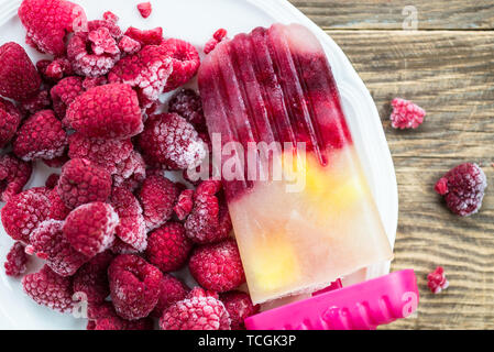Vegan fait maison à partir de jus de pomme gelée Popsicle, framboises et à la Mangue sur fond rustique foncé. Concept des aliments en été. Vue d'en haut. Banque D'Images