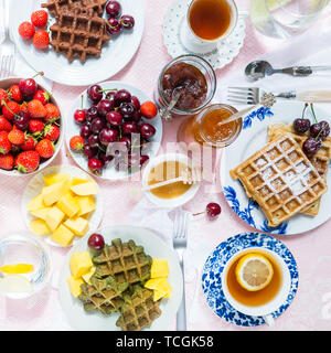 Set de table pour le petit-déjeuner avec différentes sortes de gaufres en bonne santé, de confitures et de fruits rouges Banque D'Images