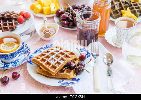 Set de table pour le petit-déjeuner avec différentes sortes de gaufres en bonne santé, de confitures et de fruits rouges Banque D'Images