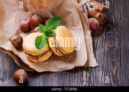 Le caramel et la cannelle macarons à la noisette et à la menthe sur la table en bois brun. Selective focus Banque D'Images