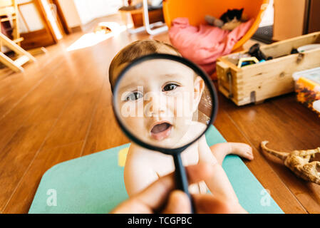 Baby face en jouant avec une loupe, ce qui en fait un drôle et tendre visage. Banque D'Images