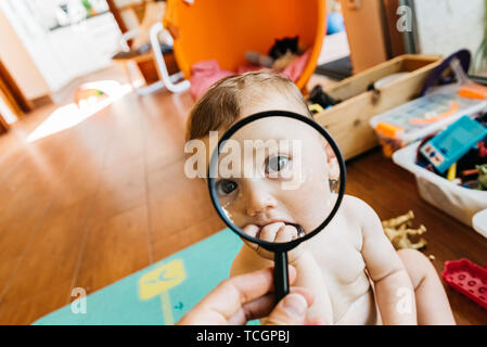 Baby face en jouant avec une loupe, ce qui en fait un drôle et tendre visage. Banque D'Images