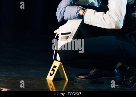 Vue partielle de l'enquêteur dans les gants en caoutchouc holding preuve lors de crime scene Banque D'Images