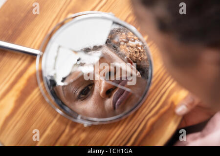 Close-up of Young Woman Looking At son visage dans un miroir cassé Banque D'Images