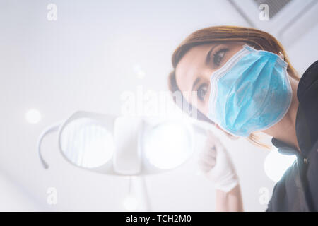 Vue de dessous de deux femmes dentistes dans le masque chirurgical et outils de maintien à l'appareil photo à. Point de vue du patient au dentiste. Banque D'Images