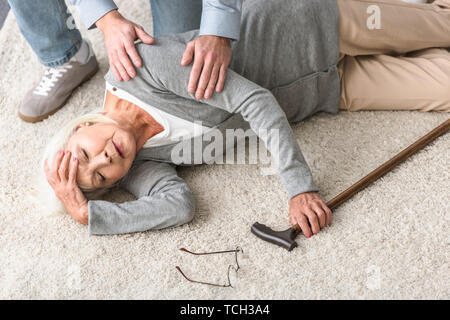 Portrait de l'homme aidant la haute mère avec attaque cardiaque tombé sur un tapis Banque D'Images