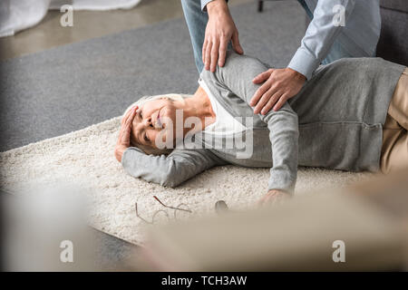 Portrait de l'homme aidant la haute mère avec attaque cardiaque tombé sur un tapis Banque D'Images