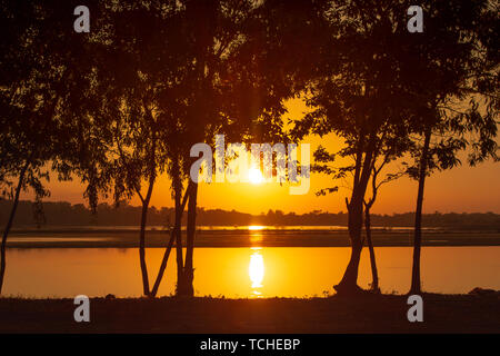 Coucher du soleil les rayons de lumière perçant à travers les arbres sur le lac Banque D'Images