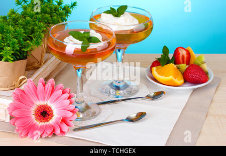 Dans les verres et gelée de fruits fruits sur table sur fond bleu Banque D'Images